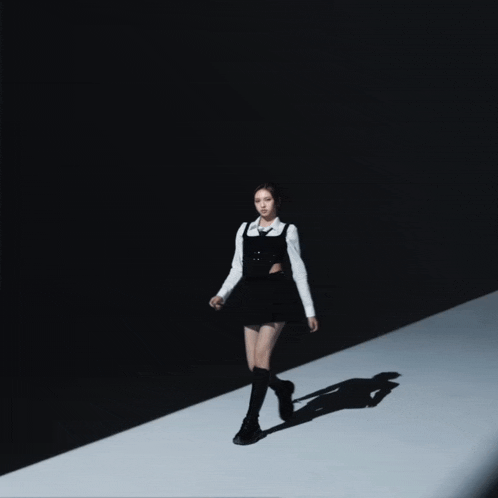 a woman in a black and white outfit is walking on a white runway