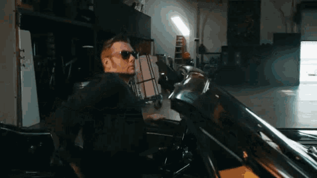 a man in a suit and sunglasses is sitting in a car .