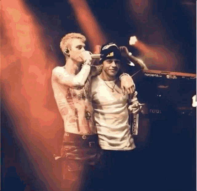 two men are standing next to each other on a stage in front of a keyboard .