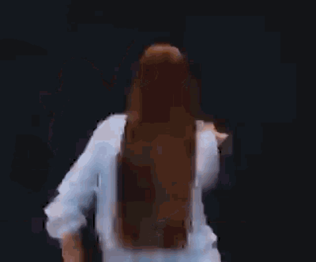 a woman in a blue shirt is dancing with her hands in the air .