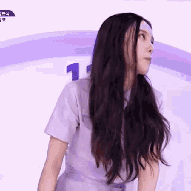 a woman with long dark hair is wearing a purple dress and standing in front of a rainbow .