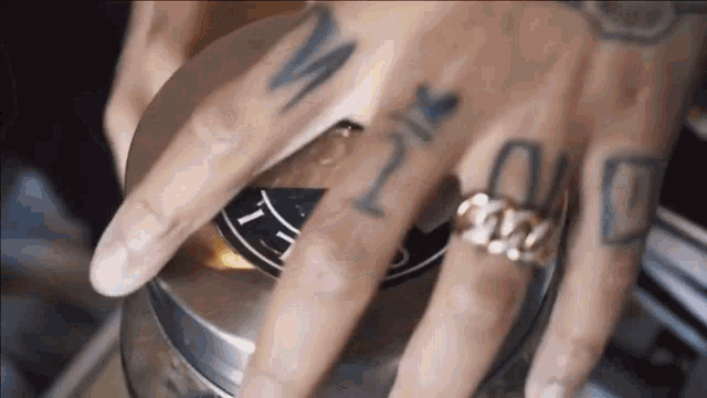 a close up of a person 's hand with tattoos and a ring