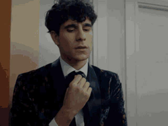 a man in a suit adjusts his tie