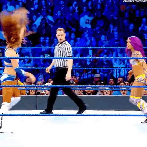 two women are wrestling in a wrestling ring while a referee walks around .