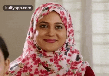 a woman wearing a floral hijab is smiling at the camera .