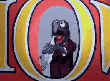 a muppet holding a fish in front of the letter o.