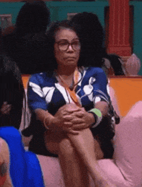 a woman wearing glasses is sitting on a couch with her legs crossed