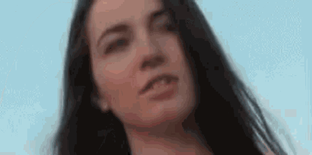 a close up of a woman 's face with long hair against a blue sky .