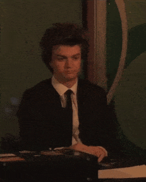 a man in a suit and tie is sitting at a table eating a sandwich