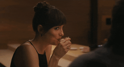 a woman in a black dress sits at a table