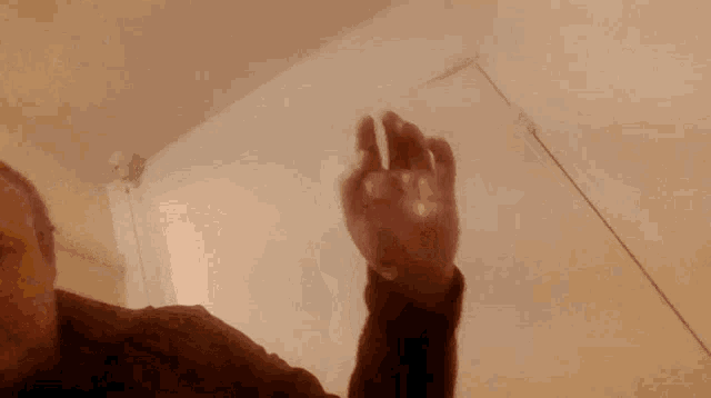 a close up of a person 's hand reaching up towards the ceiling