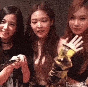 three young women are standing next to each other holding microphones and smiling .