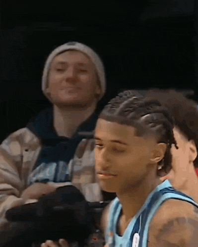 a basketball player is sitting in the stands watching a game with a camera .