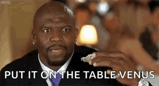 a man in a suit and tie is sitting at a table holding a piece of food .