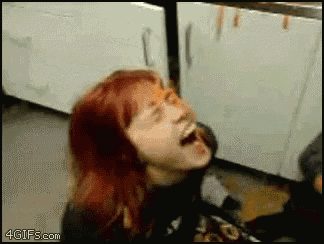 a woman with red hair is laughing in a kitchen with a 4gifs.com watermark