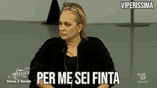 a woman is sitting in a chair with the words `` per me sei finita '' written on the screen .