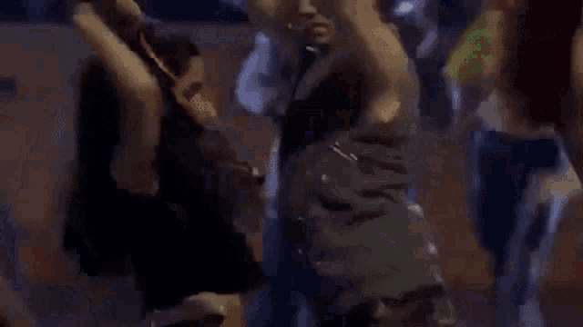 a group of people are dancing together in a dark room at a party .