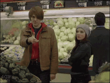 a man is giving a thumbs up in a grocery store while a woman looks on