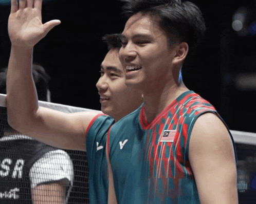 a man wearing a jersey with the malaysian flag on it waves his hand