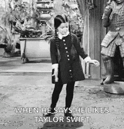 a little girl in a black dress is dancing in front of a statue of a knight .