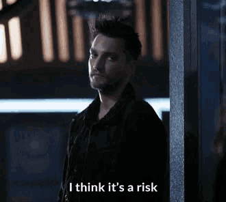 a man standing next to a pole with the words i think it 's a risk below him