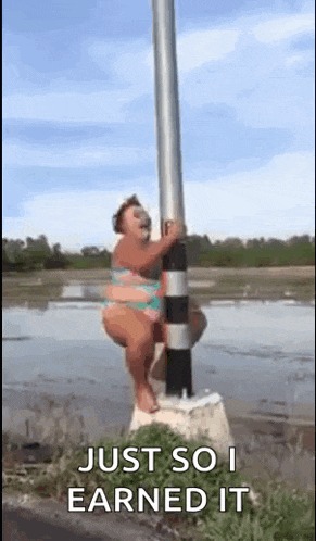 a woman in a bikini is sitting on a pole in the water .