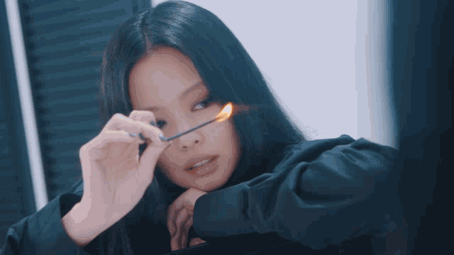 a woman in a black shirt is holding a lit match to her nose