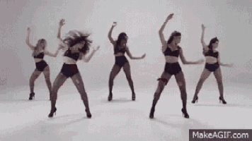 a group of women are dancing in a row in a white room .