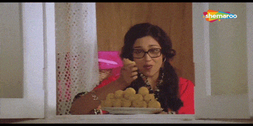 a woman in glasses is looking out a window at a plate of food with a watermark that says shemaroo