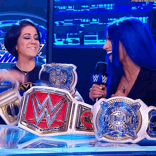 a woman with blue hair is holding a wwe title belt
