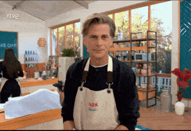 a man wearing a white apron with the name mark on it