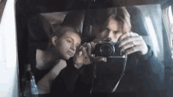 a man is taking a picture of a woman in the back seat of a car