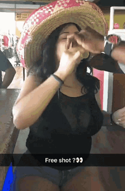 a woman wearing a sombrero is taking a shot of tequila