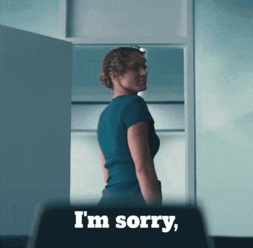 a woman in a blue shirt says i 'm sorry in front of a door