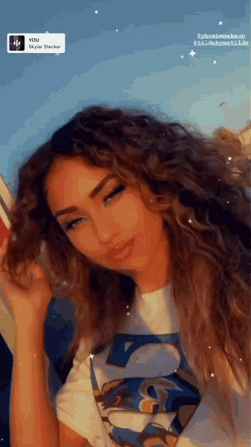 a woman with curly hair is wearing a t-shirt that says t on it