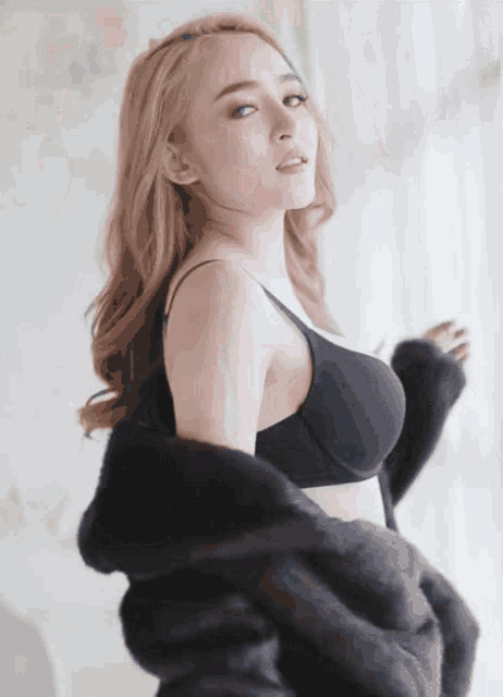 a woman is wearing a black bra and a black fur coat