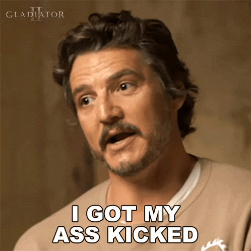 a man with a beard says " i got my ass kicked " in front of a gladiator logo