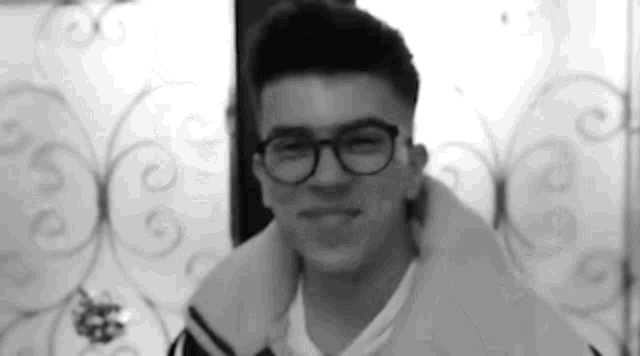a black and white photo of a man wearing glasses and a jacket .