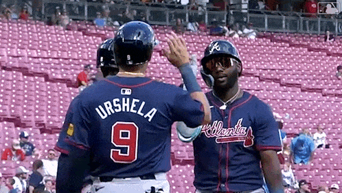 two baseball players are standing next to each other in a stadium .