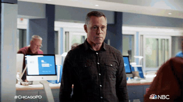 a man standing in an office with a nbc logo behind him