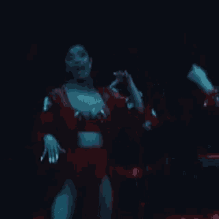 a woman in a red kimono is dancing on a stage in a dark room .