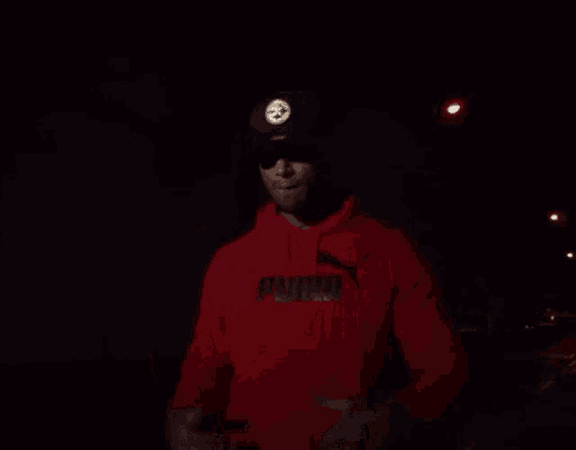 a man wearing a red puma hoodie and black hat