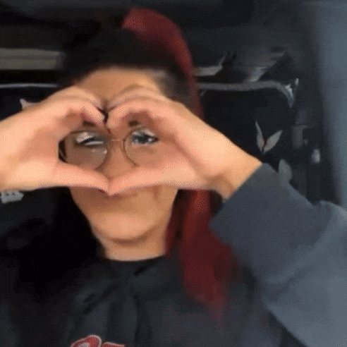 a woman making a heart shape with her hands over her eyes