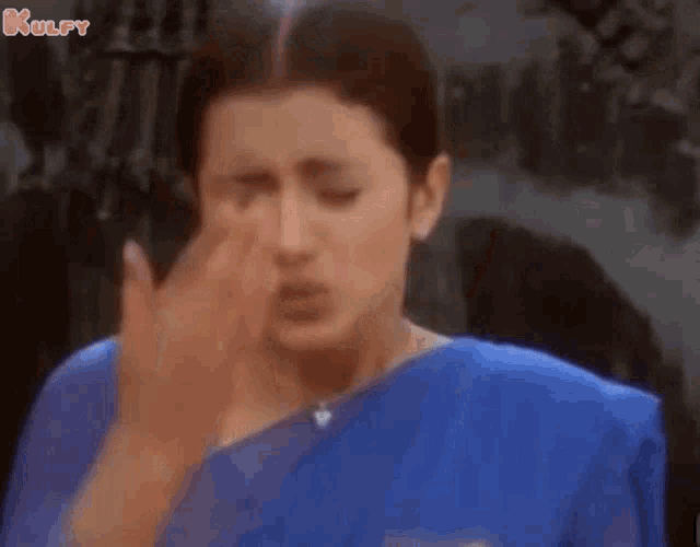 a woman in a blue saree is giving a thumbs up