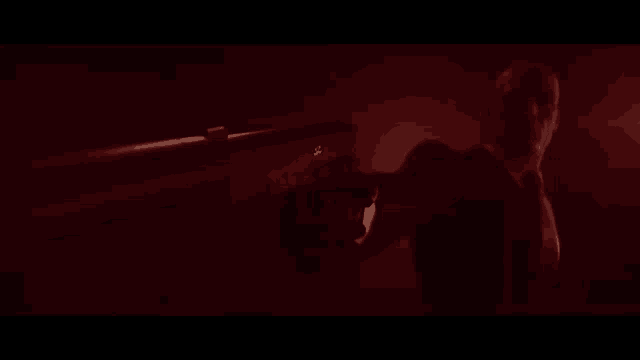a man in a mask is standing in a dark room with a red light shining on him .