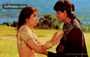 a man and a woman are standing next to each other in a field holding hands .