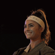 a woman wearing a headband that says ' nike ' on it smiles