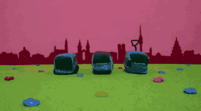 three knitted cubes are standing in a field with a pink skyline in the background