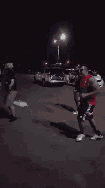 a man in a red nike shirt is running in a parking lot at night