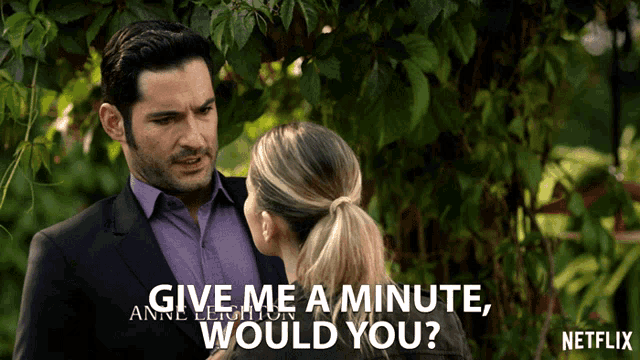 a man in a suit talks to a woman in a ponytail and says give me a minute would you .